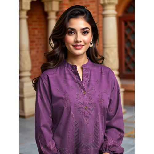 Woman wearing a purple embroidered shirt in front of a brick wall.