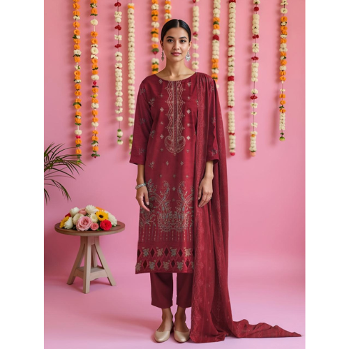 Woman in a maroon traditional outfit with floral decorations on a pink background
