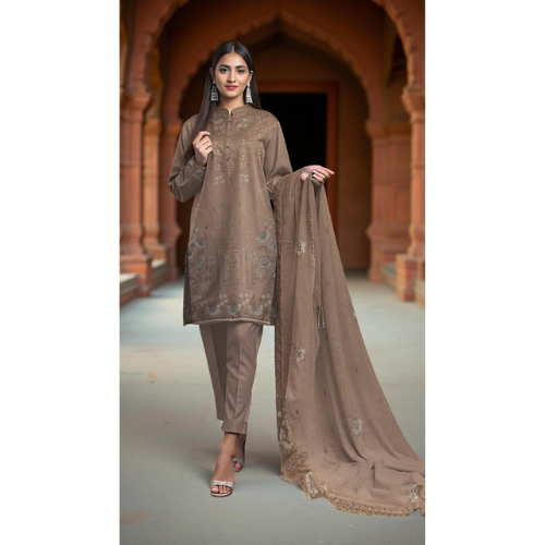 Woman in a brown traditional outfit with a dupatta standing in front of an archway.