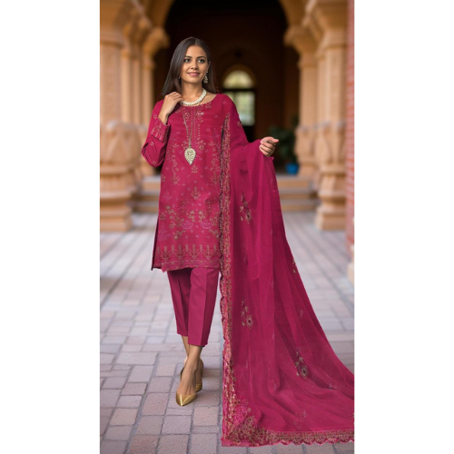 Woman in a pink traditional outfit with intricate designs in an outdoor setting.