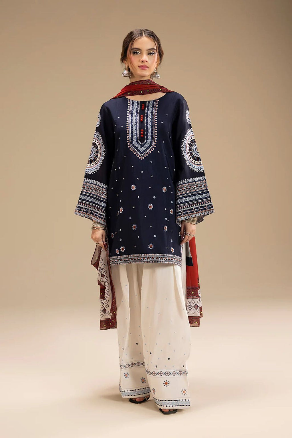 Woman wearing a navy blue embroidered kurta with white pants on a beige background