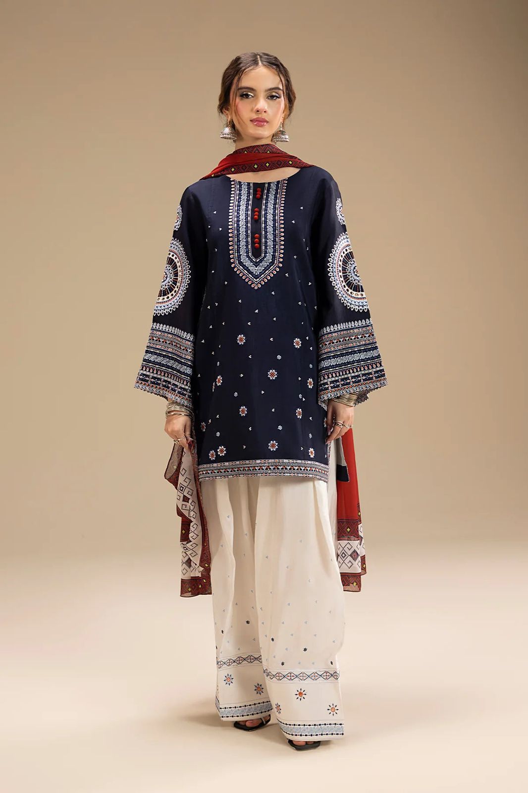 Woman wearing a navy blue embroidered kurta with white pants on a beige background